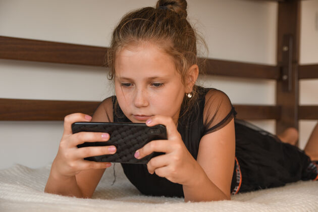 枕头技术 自由时间 交流开朗的概念穿着睡衣的teengaer 用手机上网聊天 上网 接收短信 躺在床上女士夜晚社交