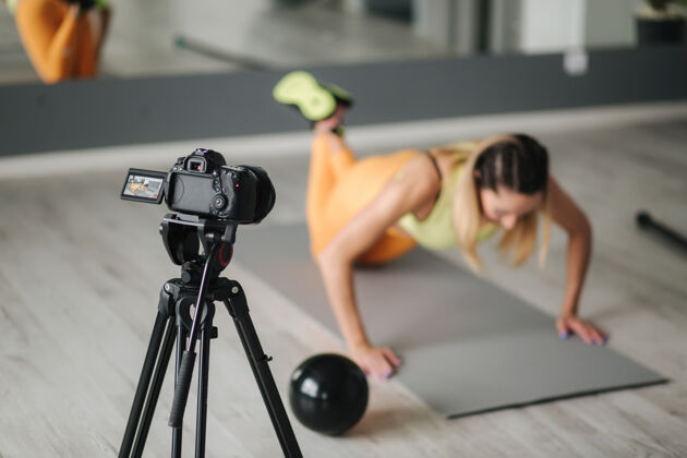 在线女健身教练在健身房训练时用摄像机录视频室内概念生活方式影响运动和娱乐放松普拉提运动