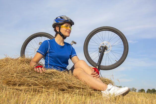 女性骑自行车的美女坐在干草的背景上自行车.自然还有伙计骑自行车的自行车自行车