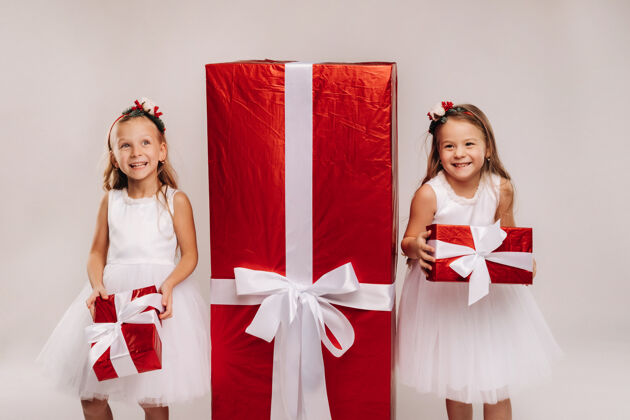 节日两个小女孩拿着圣诞礼物 白色的和巨大的礼物生活方式礼物圣诞老人