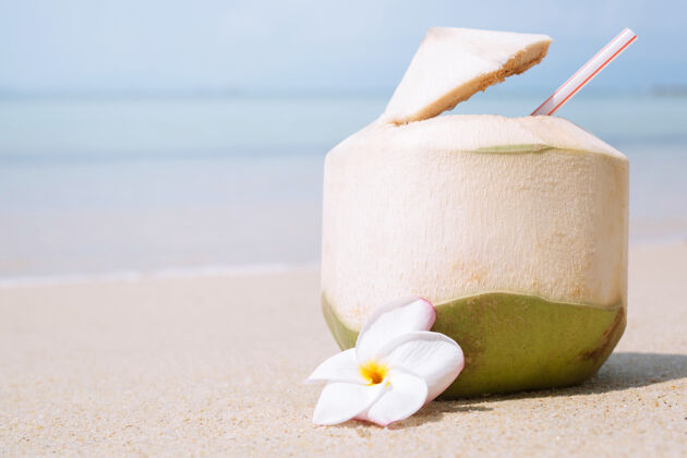 水果新鲜的椰子和吸管在沙滩上喝海洋.热带度假旅游理念海湾热带饮料
