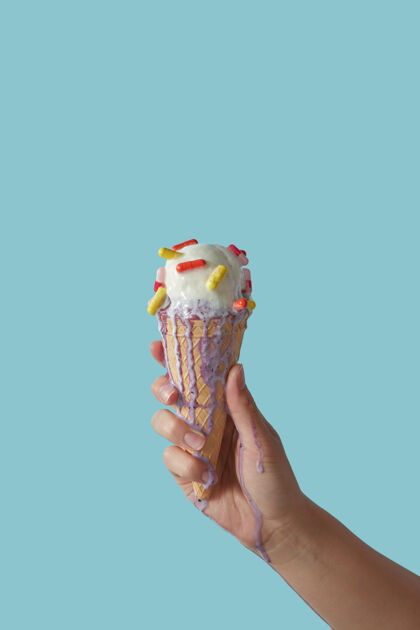 奶油一只雌性手拿着一个正在融化的水果冰淇淋 上面有彩色的药丸 背景是蓝色的空间冷夏日甜点 喉咙痛的概念球奶油控股