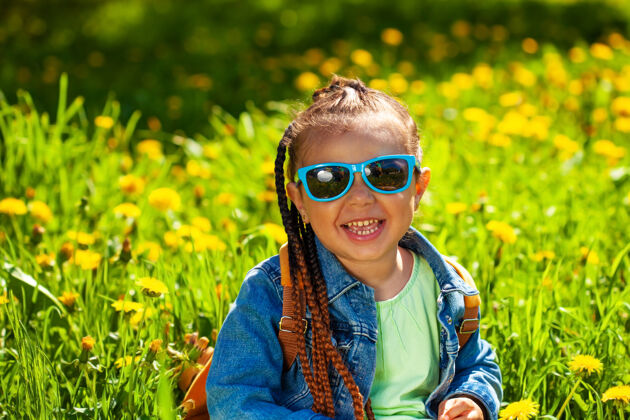阳光时尚女婴戴着墨镜坐在草地上的大自然大自行车太阳镜
