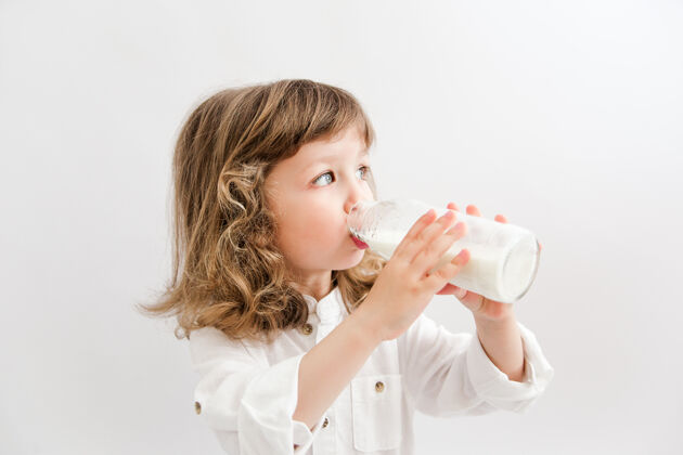 欢呼卷发蓝眼睛的漂亮女孩喝着瓶子里的牛奶健康饮食快乐