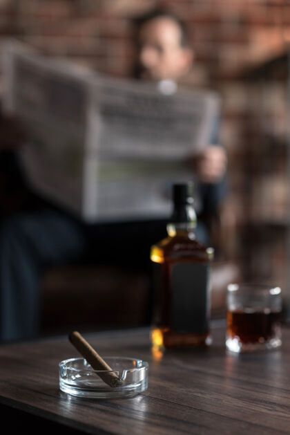 室内准备烟雾选择性焦点是一个透明的玻璃烟灰缸 里面放着一支雪茄 放在桌上靠近威士忌瓶的地方婚外情室内独处