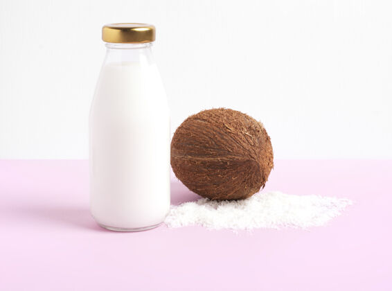 天然产品椰子奶在一个玻璃瓶中 站在一个白色和粉色的瓶子上玻璃瓶素食奶椰子奶