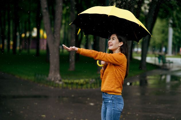 白天带伞的女人在夏日公园里享受雨水 雨天白天女性独自行走的人 小巷里的潮湿天气自然约会浪漫