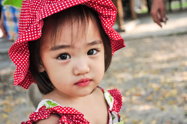 女性戴着红帽子的亚洲小女孩的户外画像女孩小人