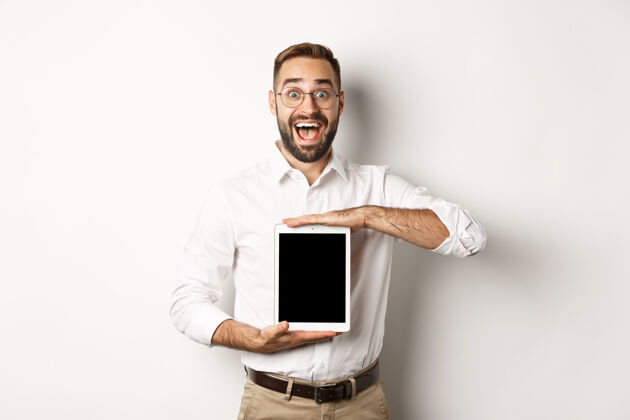 使用兴奋的男子展示数字化平板电脑屏幕 微笑着惊讶 站在白色背景上DisplayModelOffice