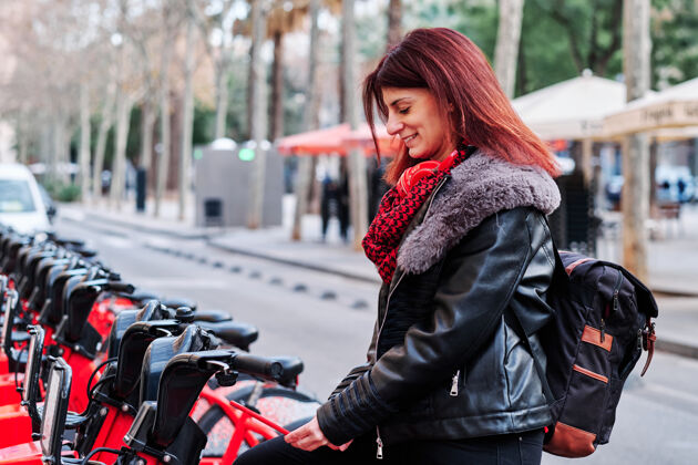 城市在一个公共停车场 一名女子正在解锁一辆自行车城市.eco-友好的交通理念自行车妇女公共
