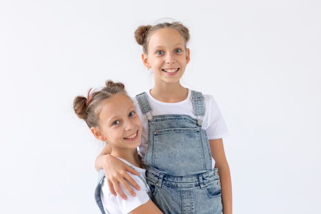 快乐家庭和爱的概念-两个微笑的双胞胎姐妹拥抱在白色背景下家庭双胞胎玩耍