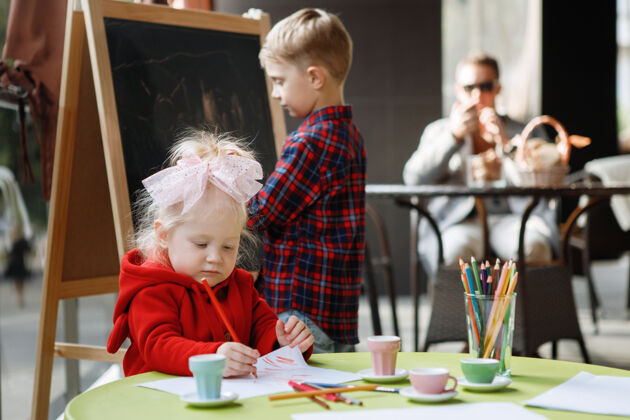可爱儿童画金发女孩坐在桌子旁 男孩站在黑板旁边房间孩子艺术家
