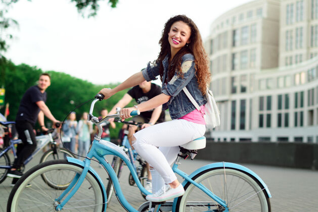 蓝色城里骑自行车的卷发美女人骑手活跃