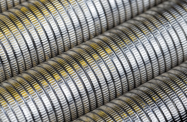 经济许多银色的圆形金属硬币被金色照亮动机利润现金