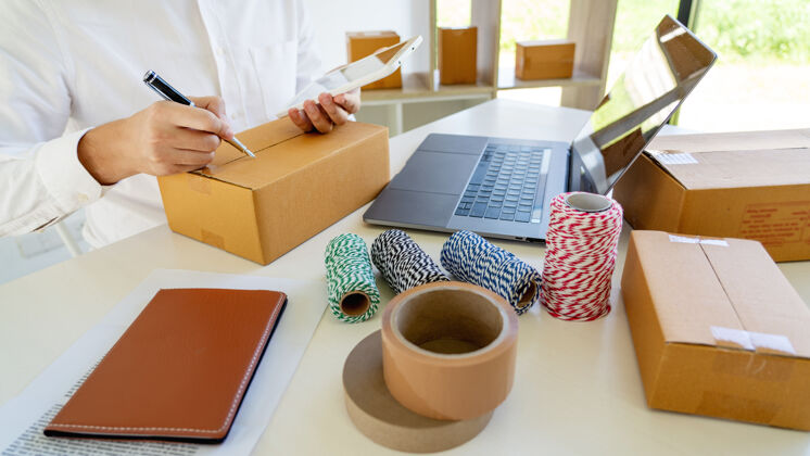 移动小企业主中小企业 年轻的亚洲男子与笔记本电脑和送货包装盒中小企业女性工作