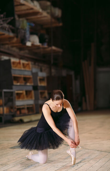 拖鞋身着黑色礼服的年轻芭蕾舞演员在幕后训练美丽专业芭蕾舞演员