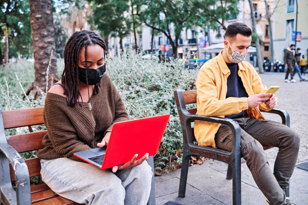 疾病人们戴着口罩 坐在户外保持距离公园新的正常生活方式.城市概念户外口罩社会距离