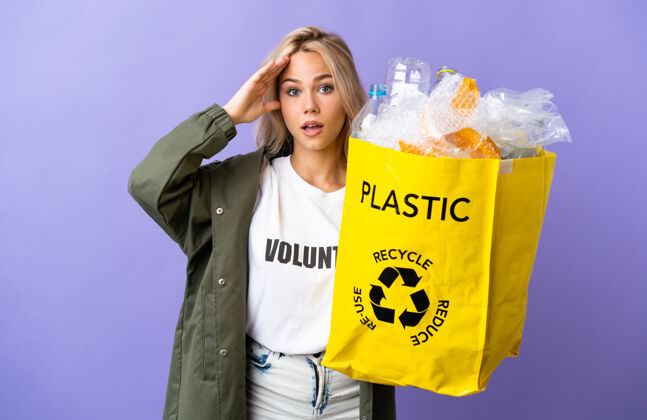垃圾俄罗斯年轻女子拿着一个装满废纸的回收袋 在紫色的背景上用惊奇的表情孤立地回收背景积极保护