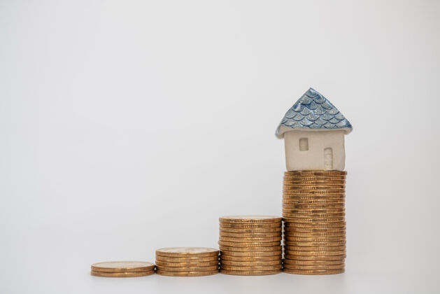 投资商业 储蓄和住房贷款概念特写在白色背景上的一堆金币上面放一个玩具陶瓷销售保险改善