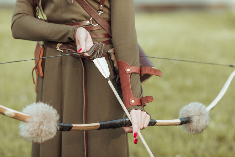 士兵拿着弓的年轻女战士用箭拉着弓弦 特写刀弓模型