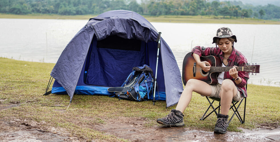 女人年轻的亚洲女性在露营时弹吉他户外自然吉他