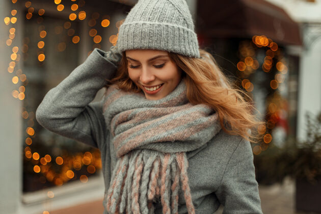 圣诞树时尚漂亮的快乐女孩穿着复古风格的外套 戴着针织时尚的帽子 戴着围巾 靠近街上的黄灯针织衣服针织品