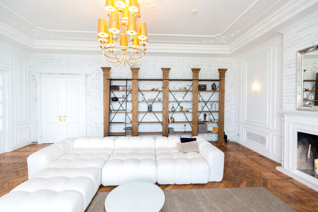豪华豪华宽敞明亮的现代室内房间白色昂贵的沙发和木制架子 白色的墙壁和一个豪华的枝形吊灯休息舒适现代