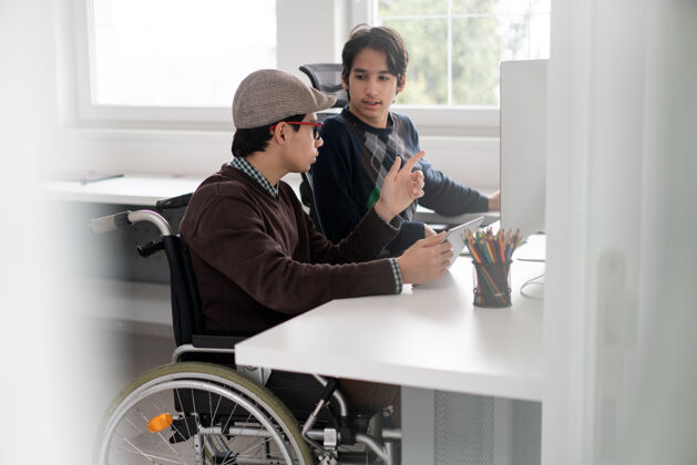 医疗保健坐在轮椅上操作电脑的年轻男生摄影师技术轮椅