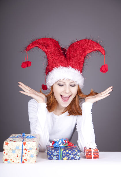玩一个戴着圣诞帽的红发女孩惊喜地拿着礼物盒可爱帽子礼物
