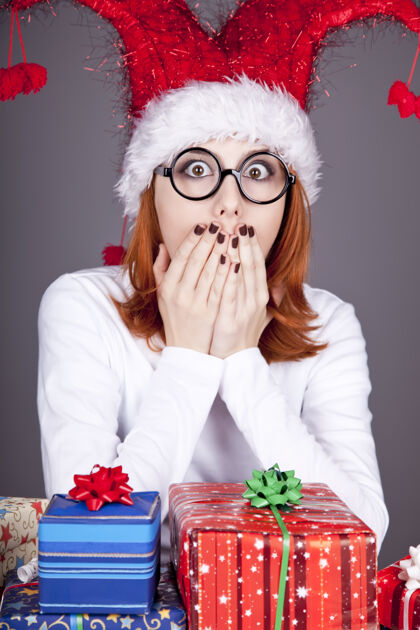 惊喜滑稽的红发女孩戴着圣诞帽 戴着带礼盒的眼镜抱着眼镜圣诞节