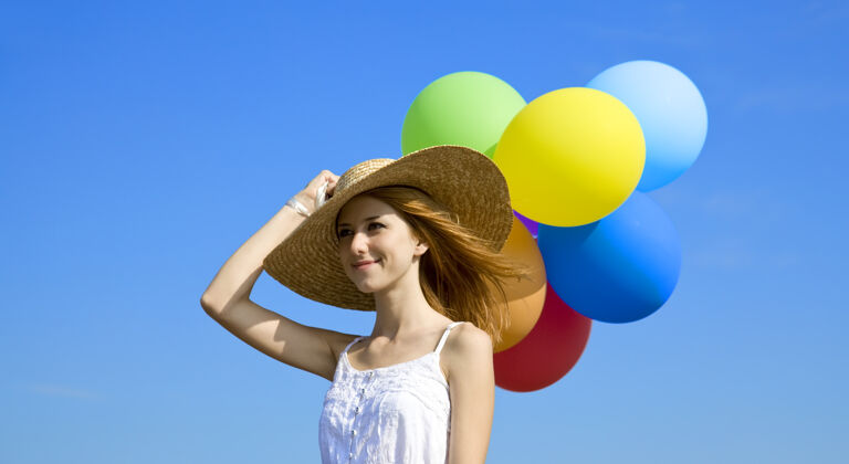 户外红发女孩带着彩色气球在蓝天上早午餐绿色自由