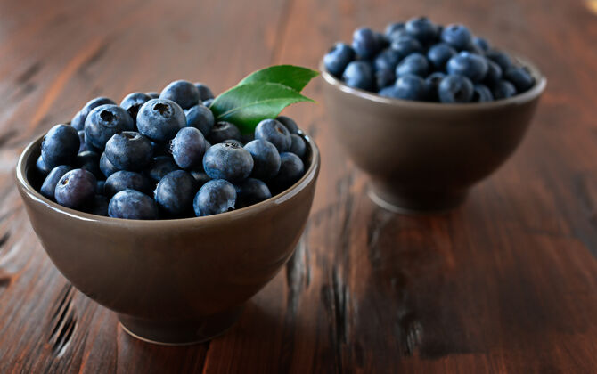 木头桌上碗里放着新鲜的蓝莓食物健康叶子