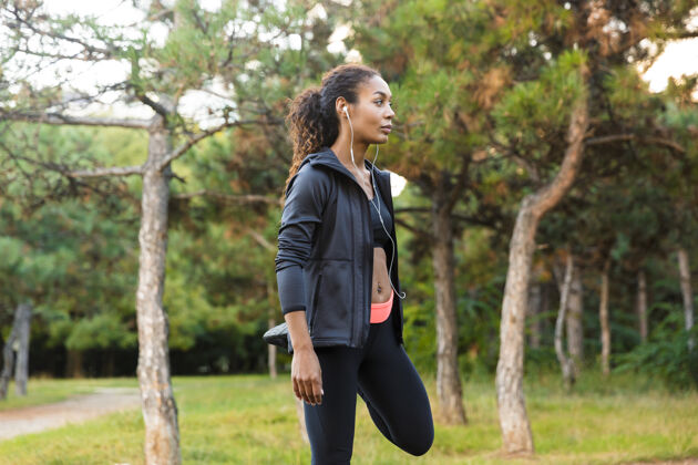 成人一位20多岁的非洲裔美国妇女穿着黑色运动服 在绿色公园里锻炼身体女运动员运动服私人教练