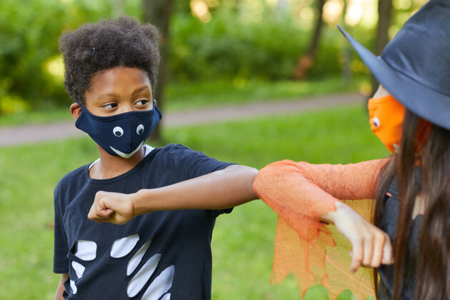 面具伪装穿着服装的非洲男孩和他的朋友在公园户外玩耍游戏友谊孩子