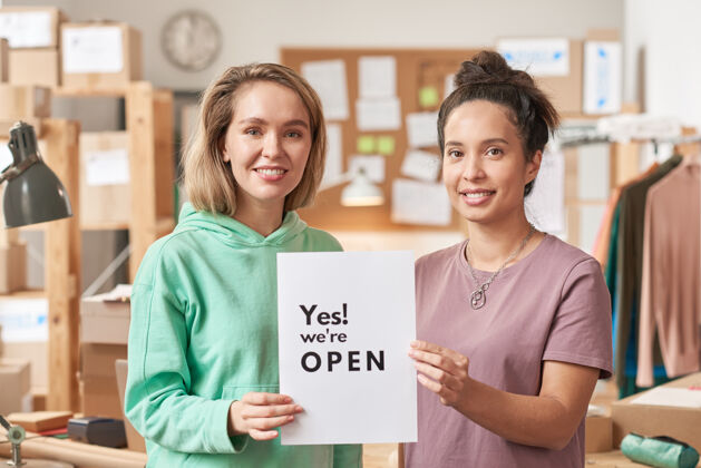展台两位年轻女性的画像 她们举着标语牌微笑着打开办公室积极情绪办公室业主