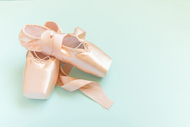传统新的粉彩米色芭蕾舞鞋与缎带隔离在蓝色背景上芭蕾培训点鞋