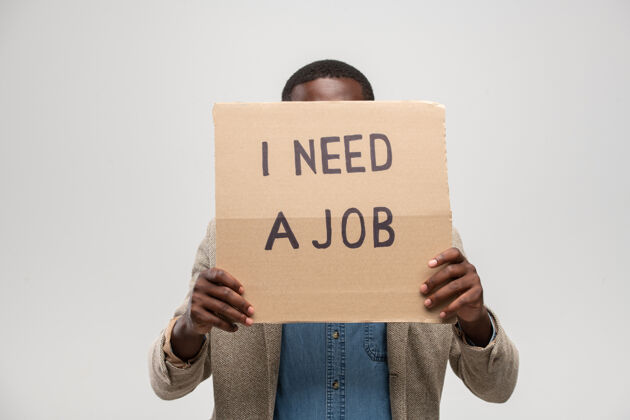隐藏一个非洲裔的年轻无业男子 站在一块硬纸板后面说他需要一份工作投票无家可归文本