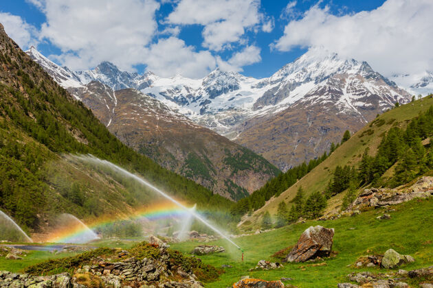 欧洲彩虹在灌溉水喷口在夏季阿尔卑斯山（瑞士 靠近泽马特）岩石景观蓝色