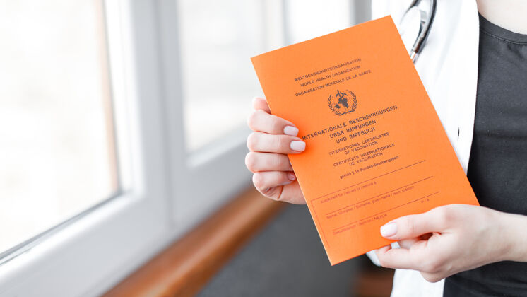 文件妇女手上有德语和英语的国际疫苗接种证书疫苗概念保护病毒证书