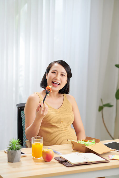 亚洲孕妇在家放松时健康吃沙拉和使用药片单亲妈妈产妇有机