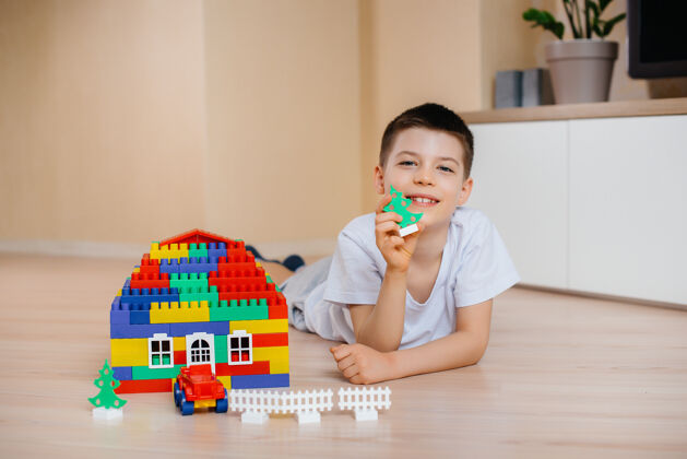 积木一个小男孩玩着一个建筑工具 为全家建造了一座大房子建造一个家庭住宅多彩幼儿建造