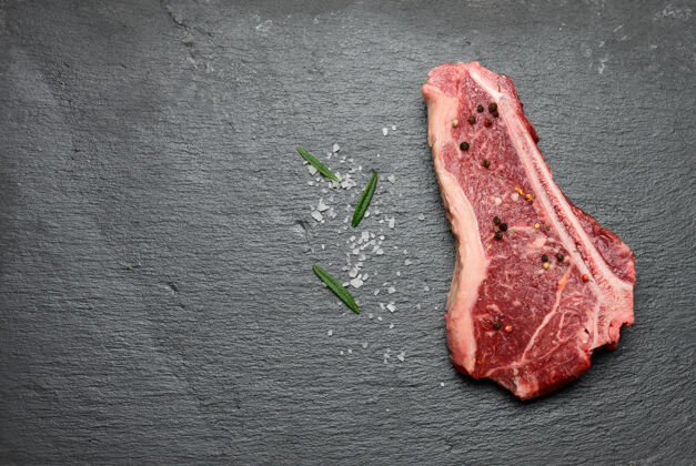 肉新鲜的生牛肉 里脊牛排躺在一块黑木板上 上面放着香料 俯视图复制空间条烧烤