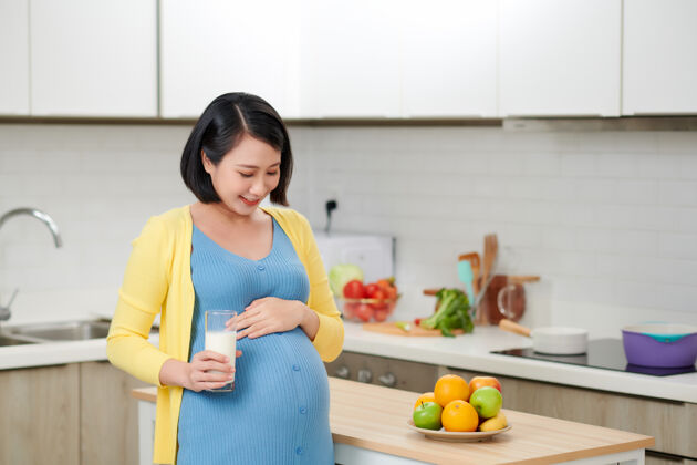 韩国人在厨房喝牛奶的喜气洋洋的女人孕妇亚洲腹部