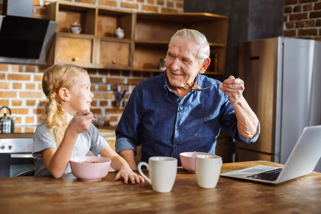 孙子开朗体贴的老人和他可爱的小孙女一起享用早餐孙子孙子大笑