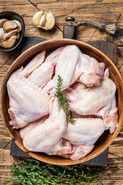 准备把生鸡翅放在一个木盘子里 放上百里香和大蒜营养鸡肉家禽