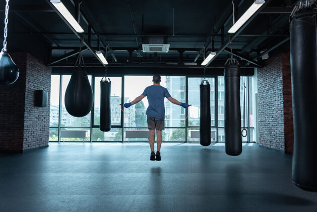 性别运动拳击手运动专业强壮的拳击手戴着蓝色的手腕 一边跳绳一边刻苦训练压力动作拳击圈