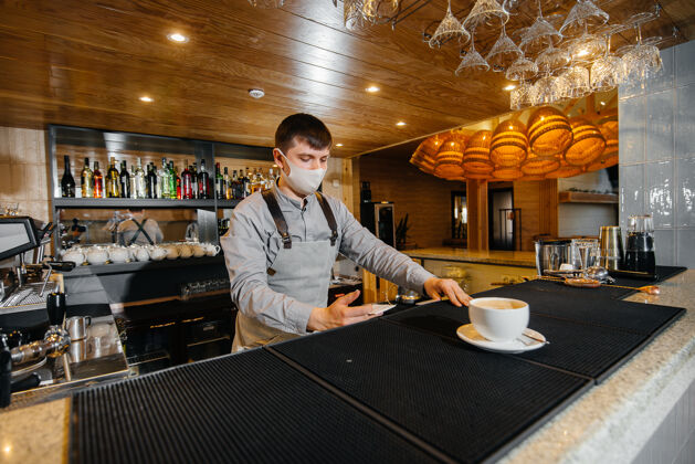 制服在流感大流行期间 在现代咖啡馆 一位戴着美味有机咖啡面具的咖啡师提交了申请咖啡师早餐流行