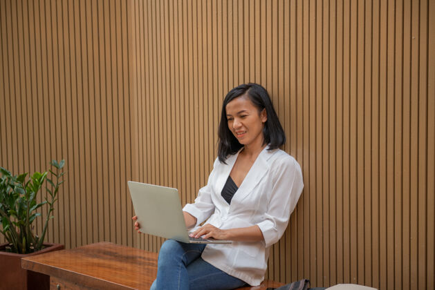 持有可爱的年轻女商人的肖像户外笔记本电脑自由职业者女人商务妇女