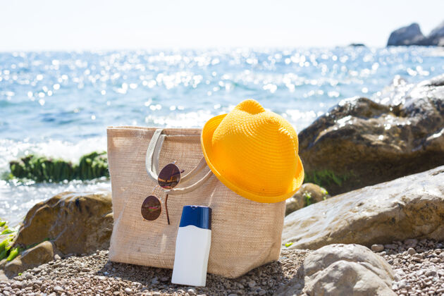 海洋海边的鹅卵石海滩上放着一个装着白色防晒霜的沙滩包实体模型放松海岸石油