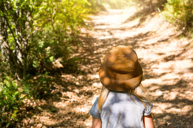 孤独一个戴草帽的小女孩走在森林里的小路上路线自由徒步旅行者